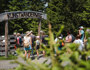 Besucher:innen beim Eingang zum Kunstwanderweg am Asitz in Leogang. | © Michael Geißler