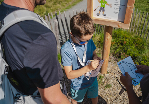 Kind füllt die Rätselkarte bei Leos Rätseljagd am Berg der Sinne in Leogang aus – interaktives Naturerlebnis für Familien in Leogang | © Michael Geißler