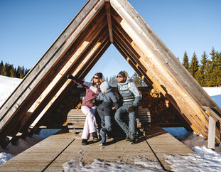 Gemeinsame Wintermomente genießen: Familie entspannt an einem Aussichtspunkt in Saalfelden Leogang – Natur, Sonne und alpine Ruhe. | © Saalfelden Leogang | Alpine Vision