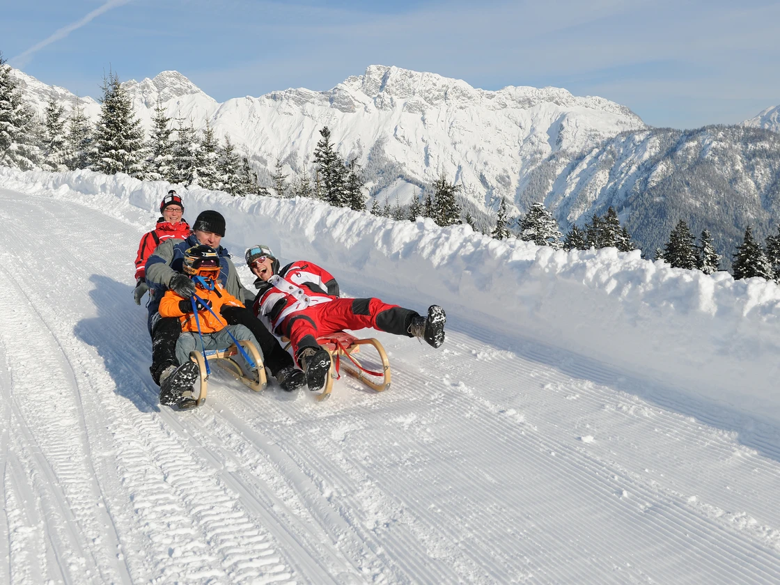 Familie beim Schlittenfahren auf der Rodelbahn am Biberg