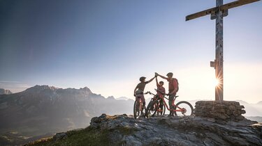 Mountainbiker auf dem Berggipfel bei Sonnenaufgang in Saalfelden-Leogang | © Klemens König