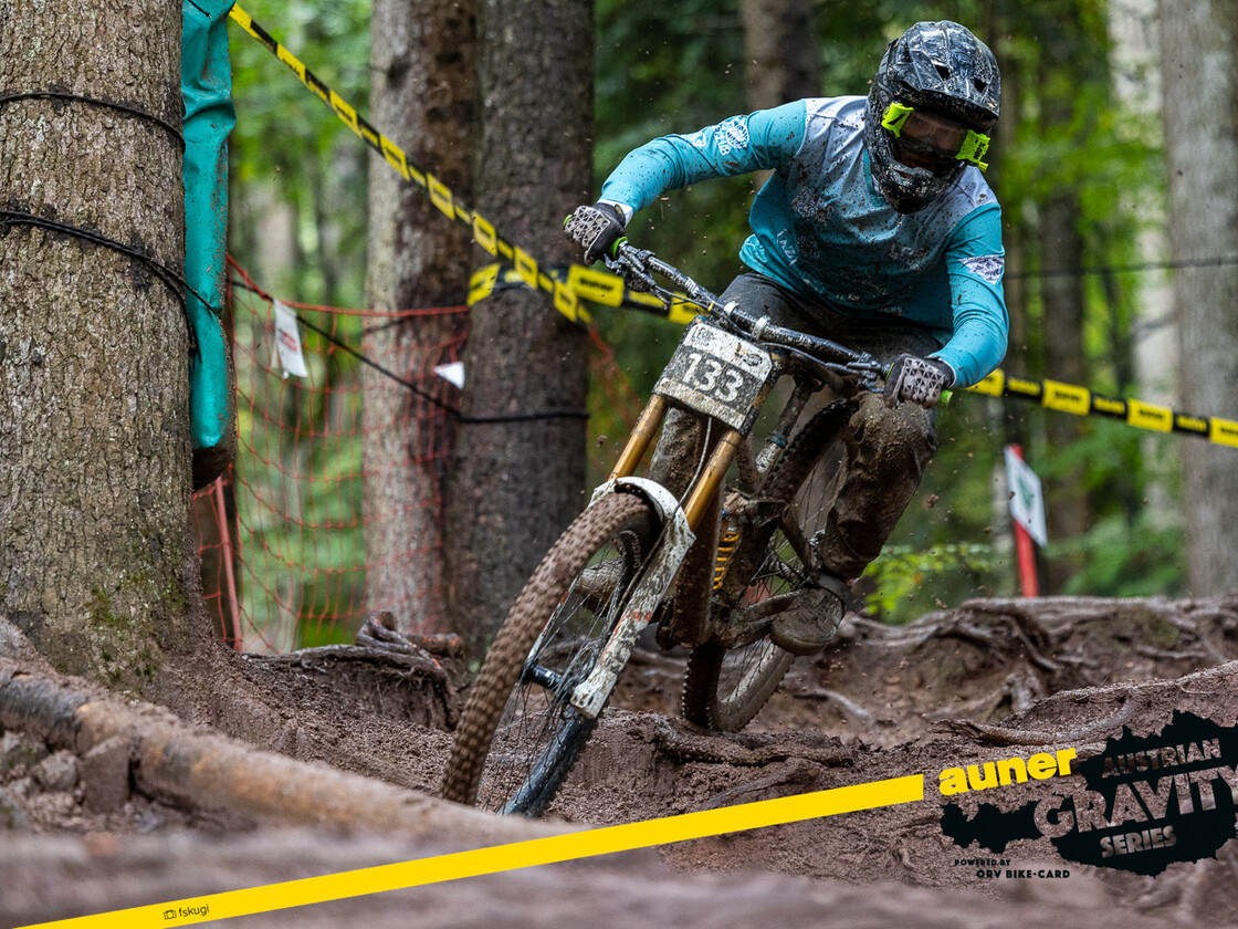 Austrian Gravity Series – Wurzelpassage im Renntempo | © Austrian Gravity Series  Downhill-Racer mit Startnummer 133 kämpft sich durch eine rutschige Wurzelpassage im dichten Wald während der Austrian Gravity Series, voll konzentriert auf die Ideallinie. | © Austrian Gravity Series