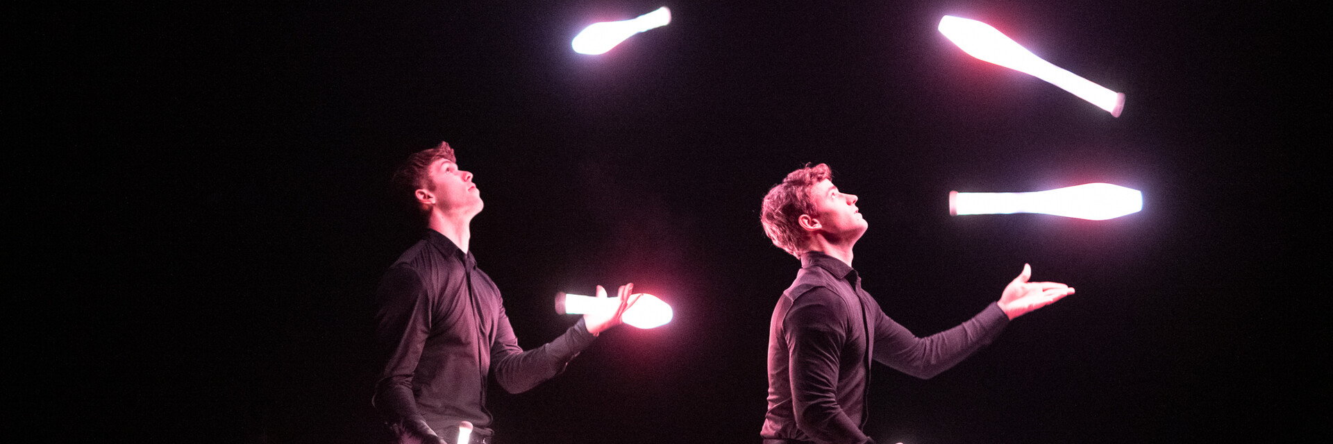 Vor schwarzem Hintergrund sieht man 2 junge Herren mit jeweils 4 LED Keulen jonglieren | © cb photography