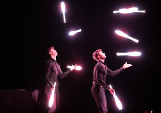 Vor schwarzem Hintergrund sieht man 2 junge Herren mit jeweils 4 LED Keulen jonglieren | © cb photography