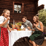 Family having snack at mountain hut in Saalfelden-Leogang