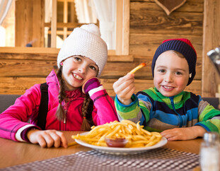 Kinder beim Mittagessen auf der Skihütte | © Mirja Geh