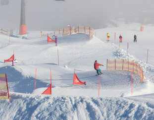 Überblick über den Funcross am Schanteilift in Leogang mit Gondeln der Steinbergbahn und perfekt präparierter Familienpiste. | © Daniel Roos