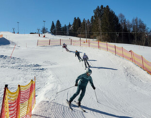 Familie fährt durch eine Steilkurve im Funcross am Schanteilift in Leogang und genießt abwechslungsreichen Pistenspaß im Skicircus Saalbach Hinterglemm Leogang Fieberbrunn. | © Daniel Roos